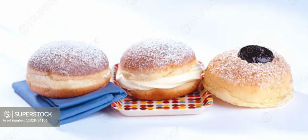 Three doughnuts with plum jelly, vanilla cream and jam