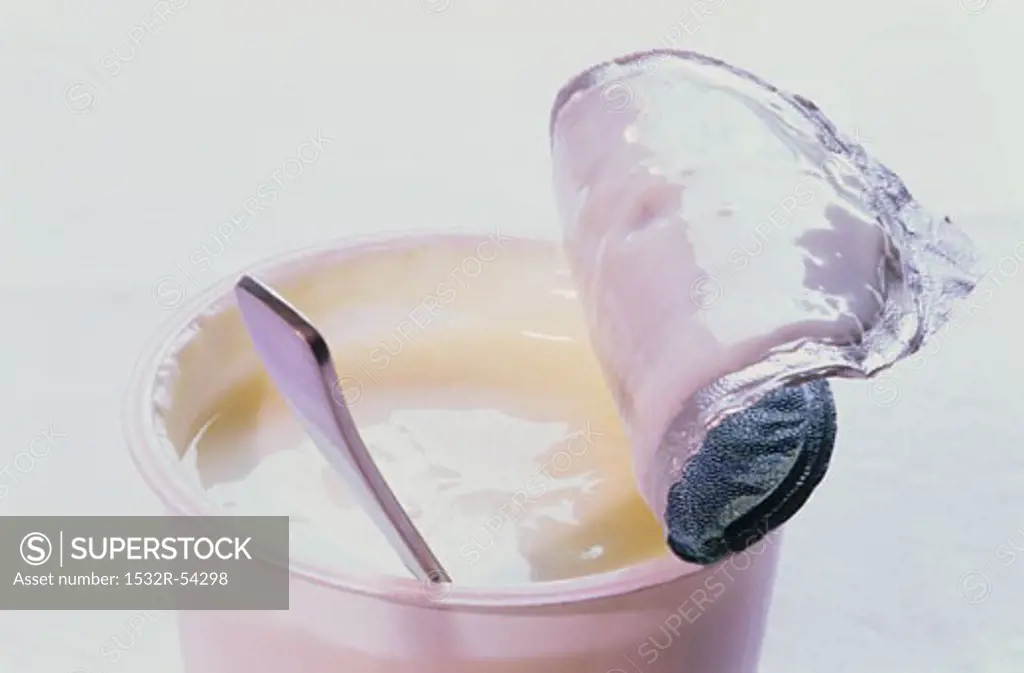 Natural yoghurt in opened pot with spoon