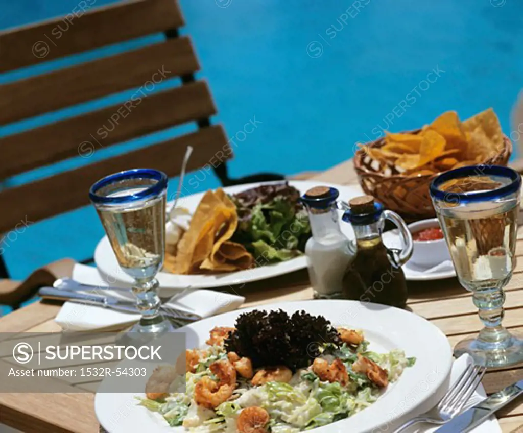 Prawn salad and crisps on laid table out of doors