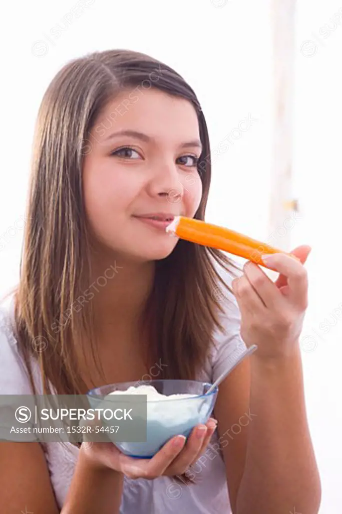 Girl eating a carrot with yoghurt dip