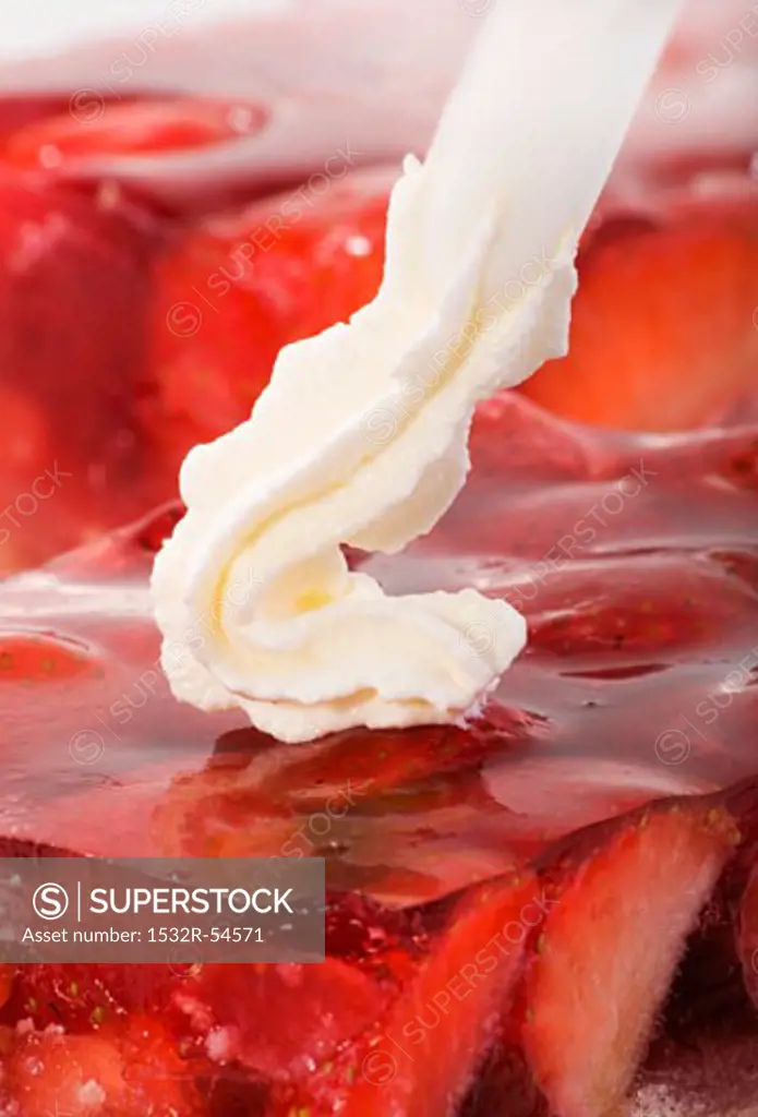 Piping cream onto strawberry cake