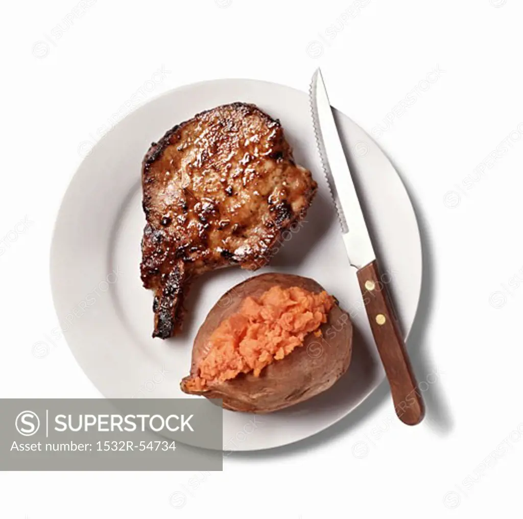 Pork Chop and Baked Sweet Potato on White Plate; White Background