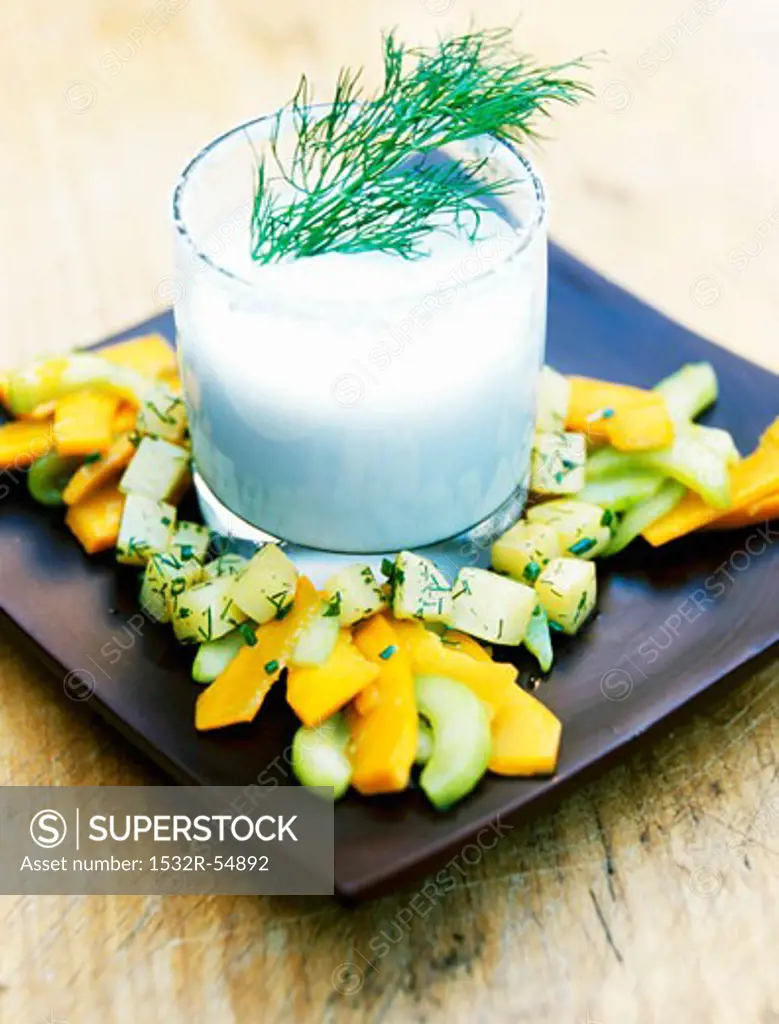 Coconut and cauliflower cream soup in a glass with a cucumber and pumpkin salad