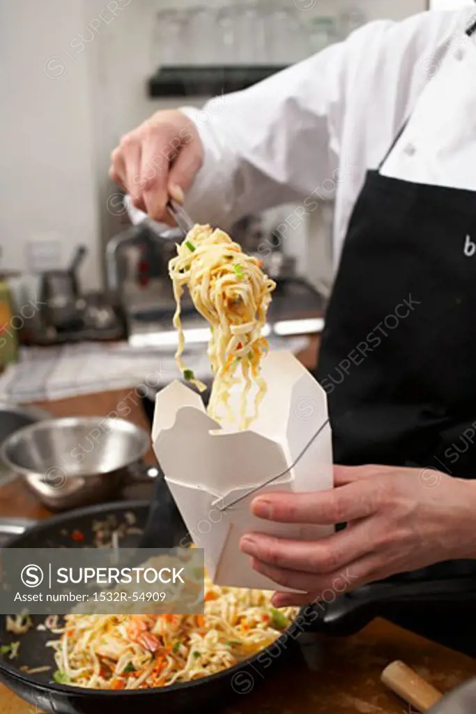 Filling a takeaway box with Asian noodles