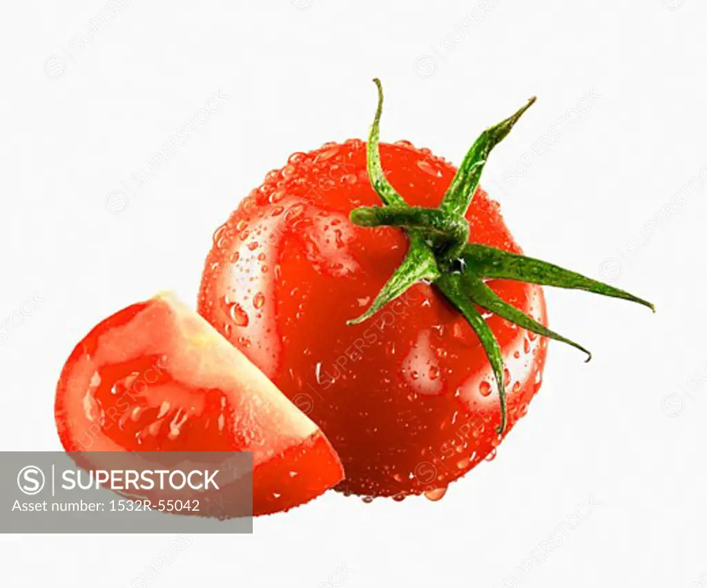 One whole and one tomato wedge with drops of water
