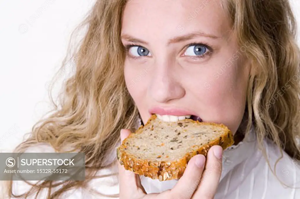 Young woman bitung into a slice of grannary bread