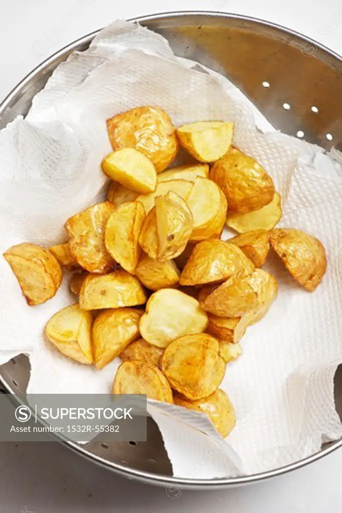 Deep fried potatoes being dried on kitchen paper