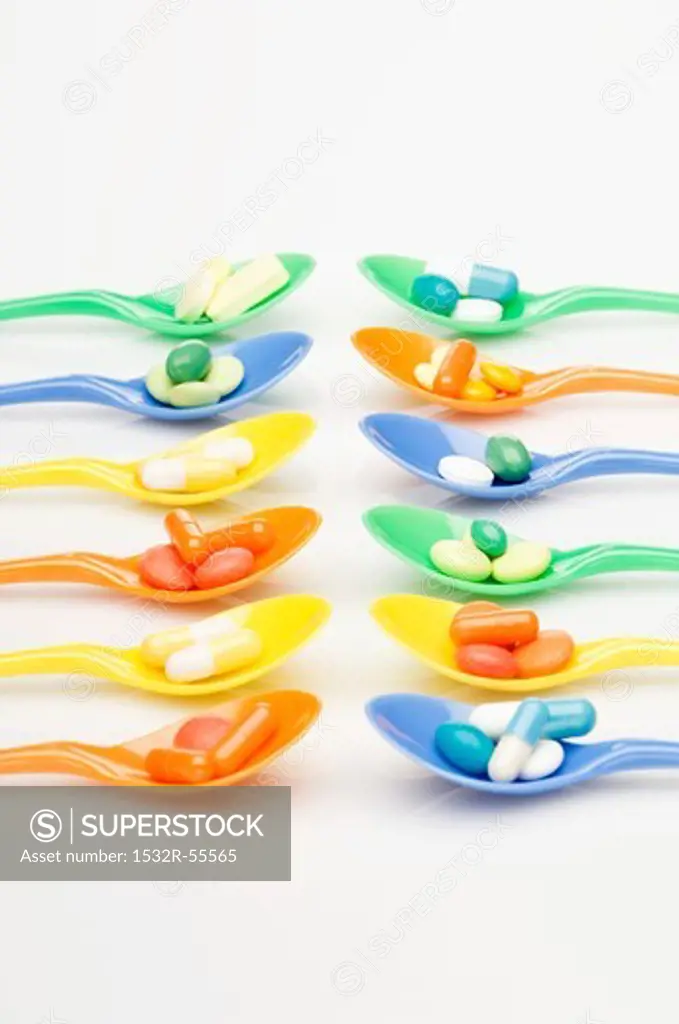 Rows of spoons with vitamin tablets