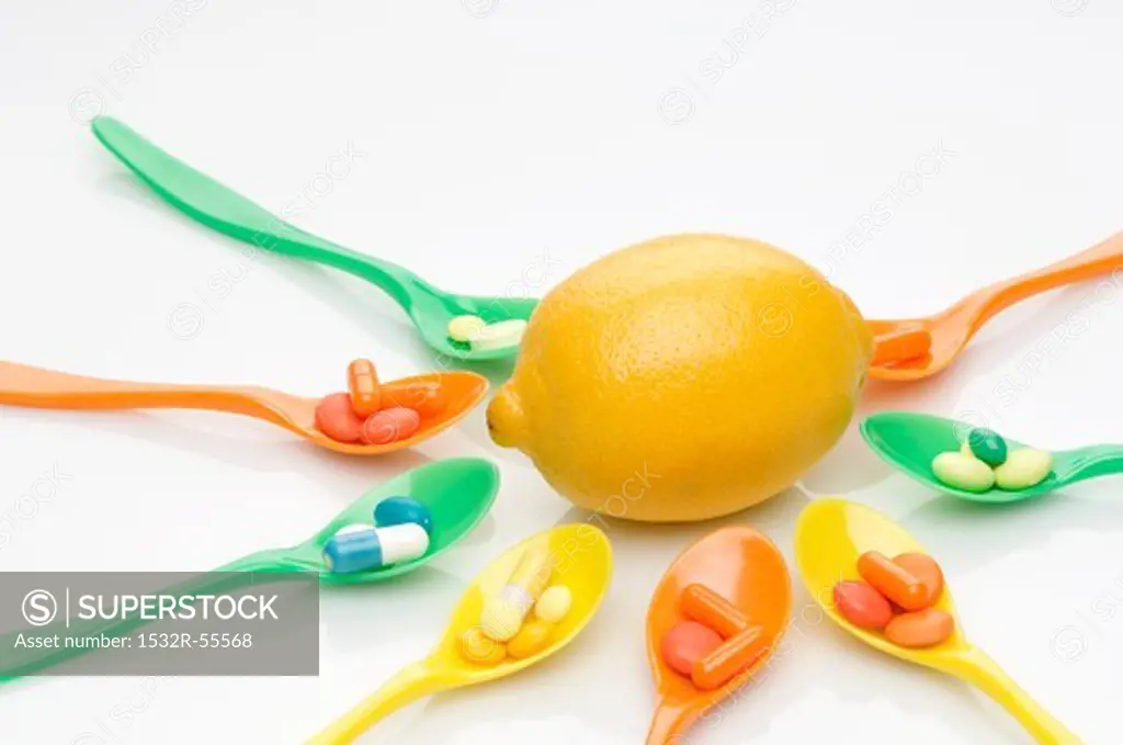 Spoons with vitamin tablets surrounding a lemon