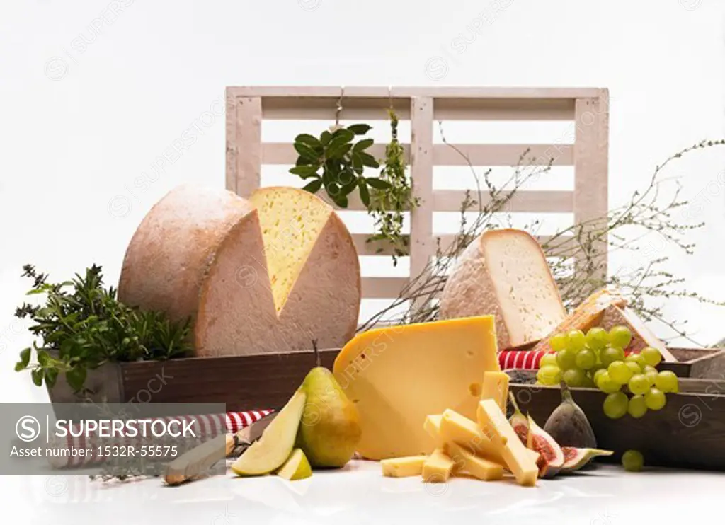 An arrangement of cheeses with fruit and herbs