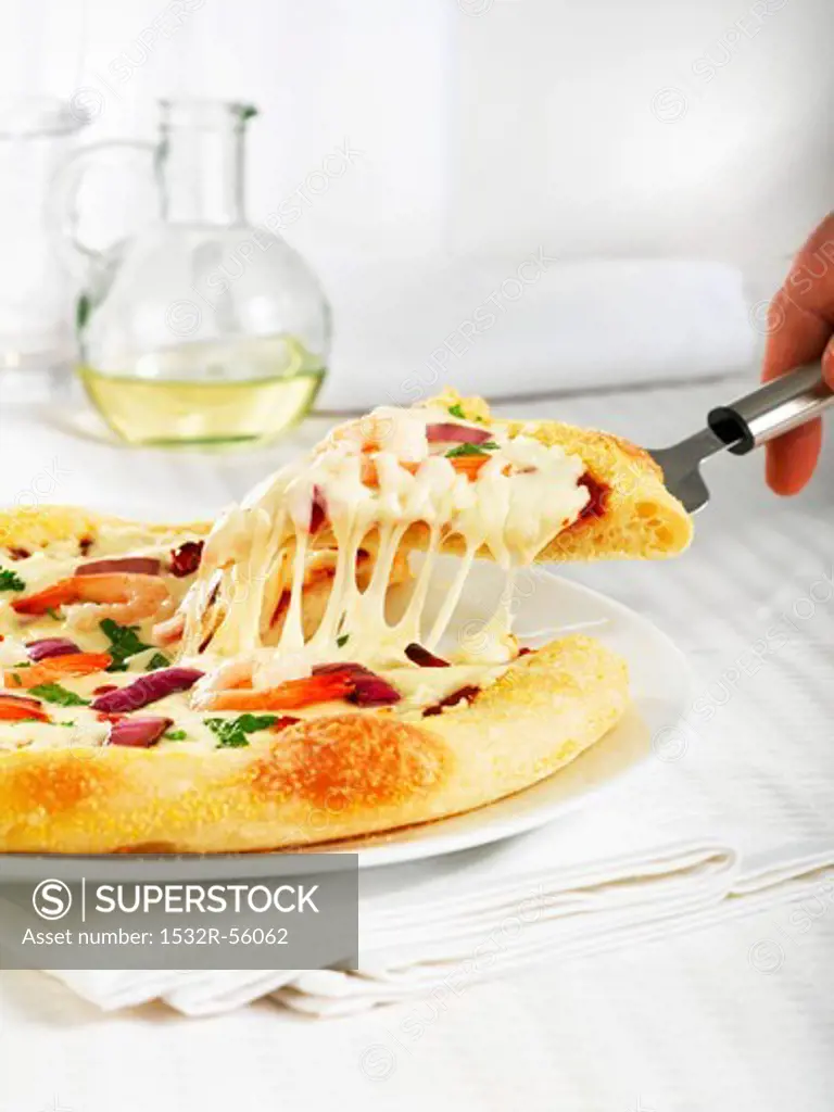 Serving a Piece of Cheesy Pizza Topped with Shrimp and Veggies