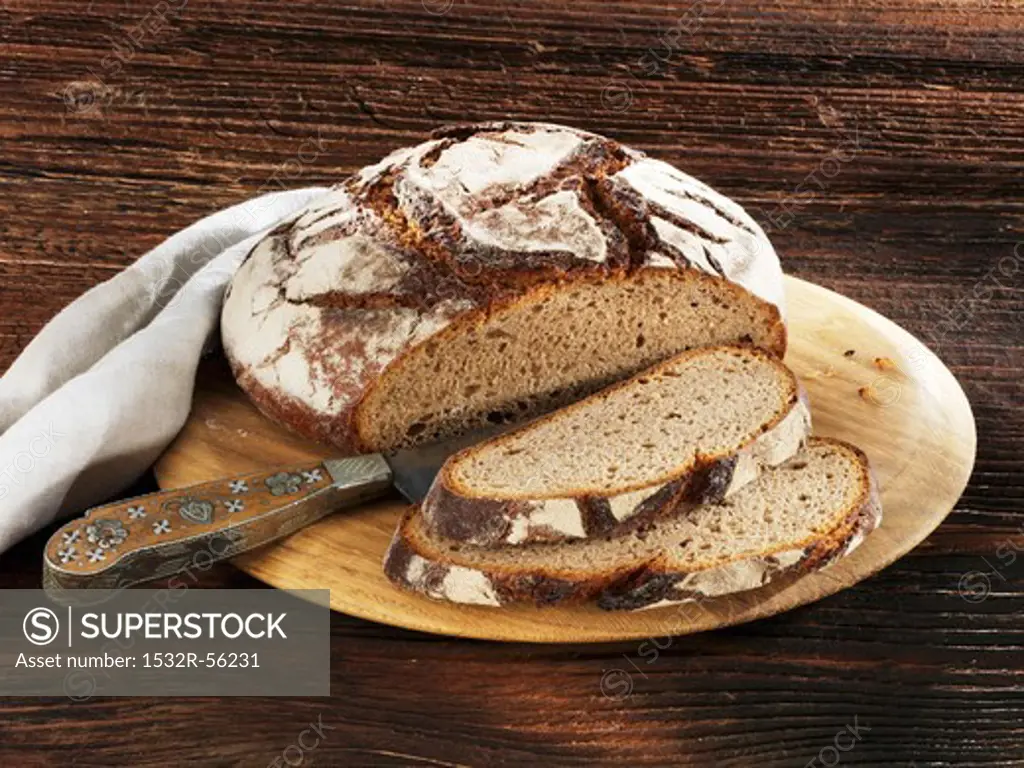 Rustic country loaf on a wooden plate, sliced