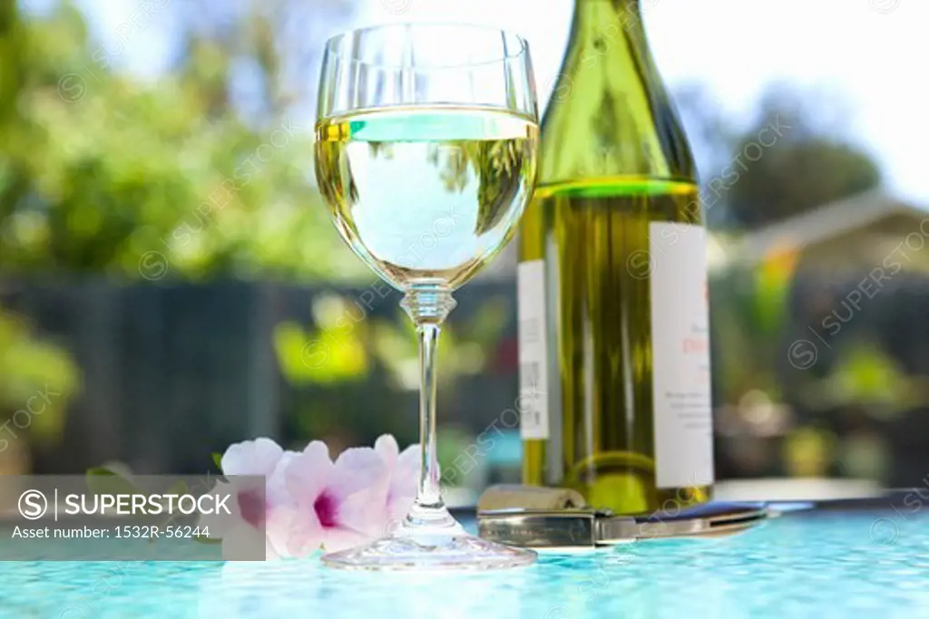 Glass and Bottle of White Wine on an Outdoor Table; Poolside