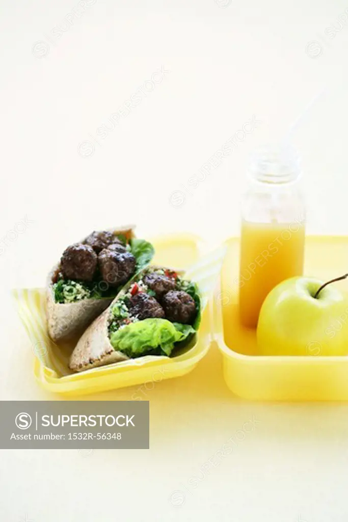 Pita bread with meat balls and tabbouleh, an apple and a smoothie in a lunchbox