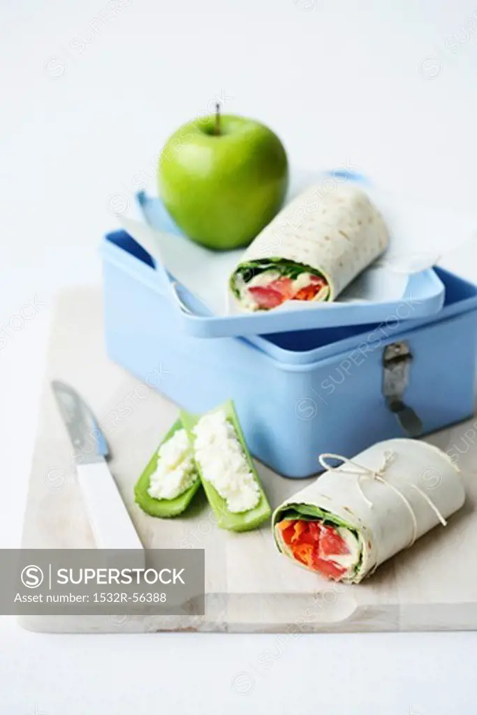 A lunchbox with wraps and an apple