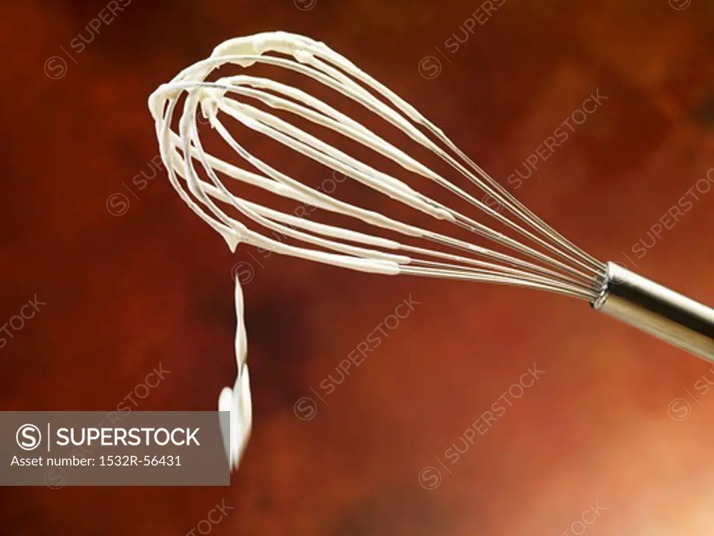 A whisk with whipped cream