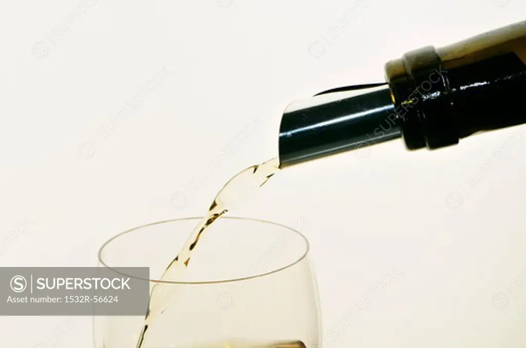 White Wine Pouring from Bottle into Glass; White Background