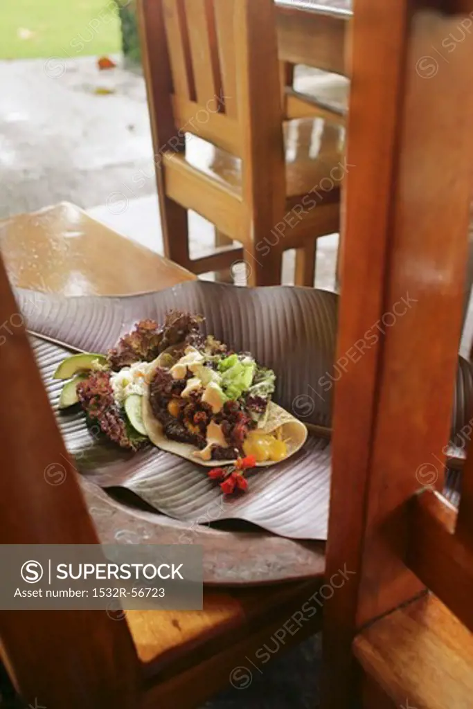 Burrito on a leaf on a wooden bench