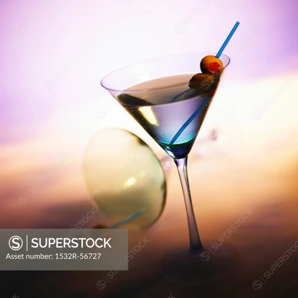 Vodka Martini with Olives; Tipped Martini Glass in Background