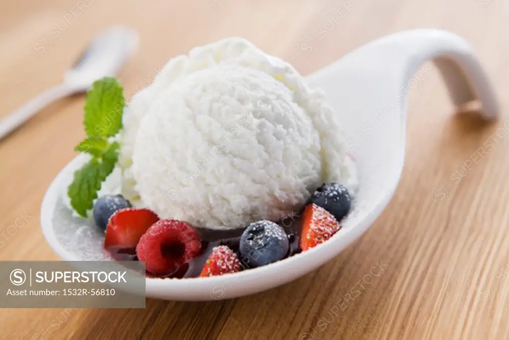 A scoop of yogurt ice cream on a spoon with berries