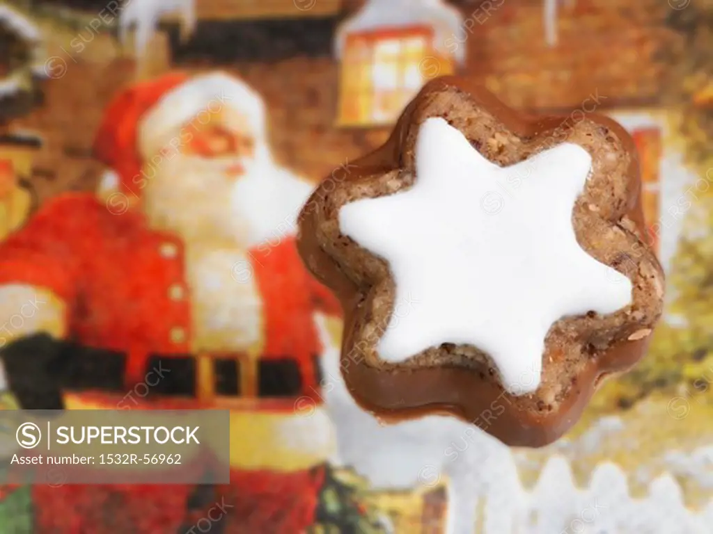 A cinnamon star with a Father Christmas figure in the background