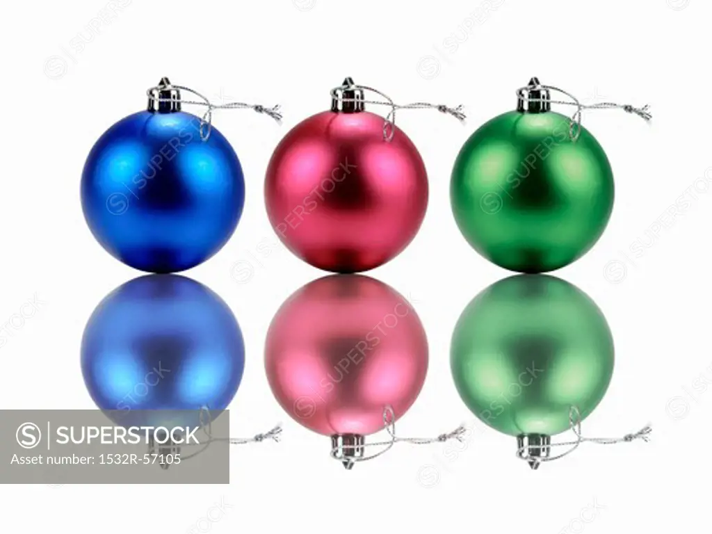 Three Christmas tree baubles and their reflections