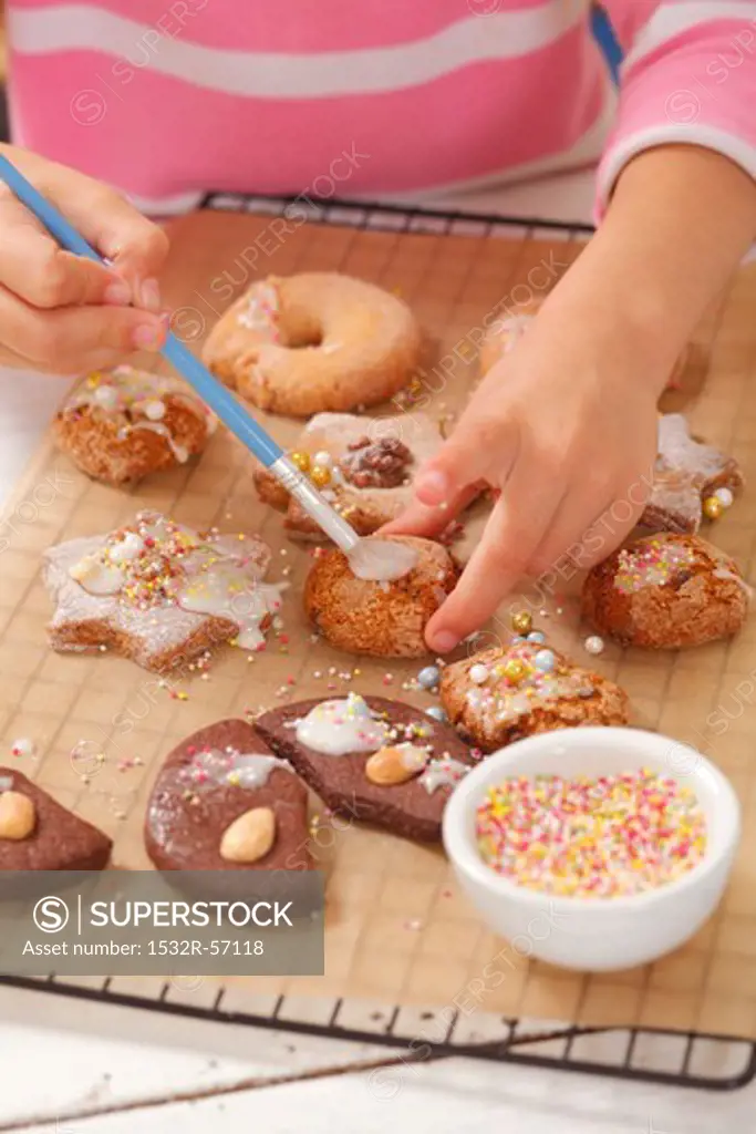 A girl decorating biscuits with icing sugar