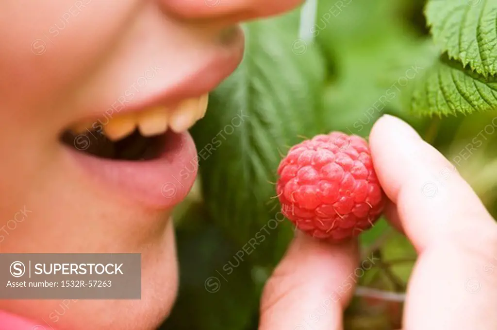 A woman eating a raspberry