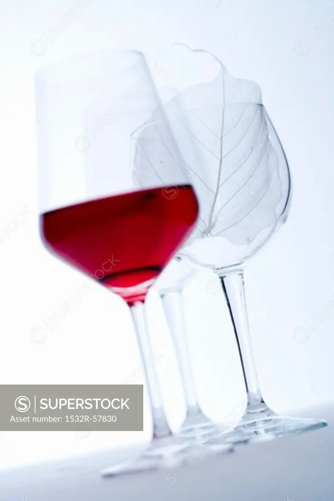 Glass of red wine and empty wine glasses