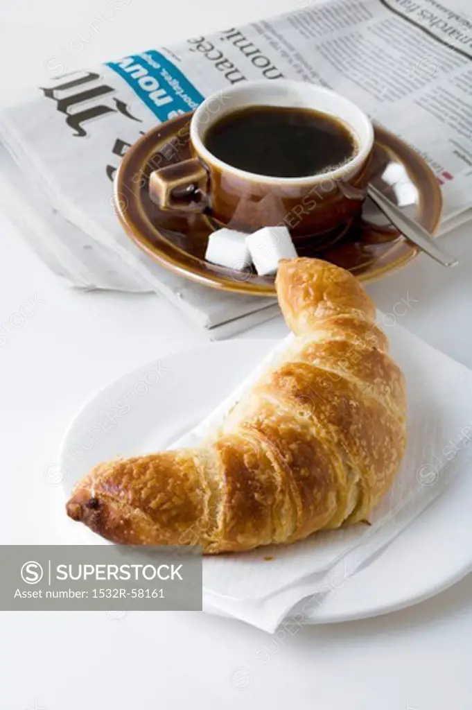 Croissant, coffee and newspaper