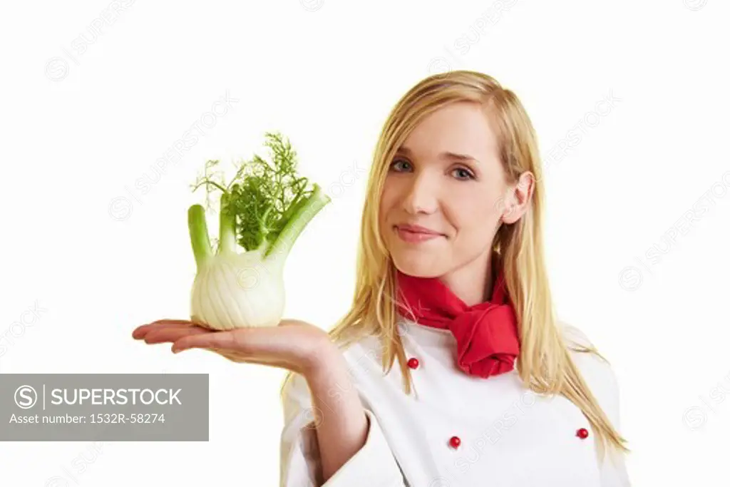 Blond female chef balancing fennel bulb on her hand
