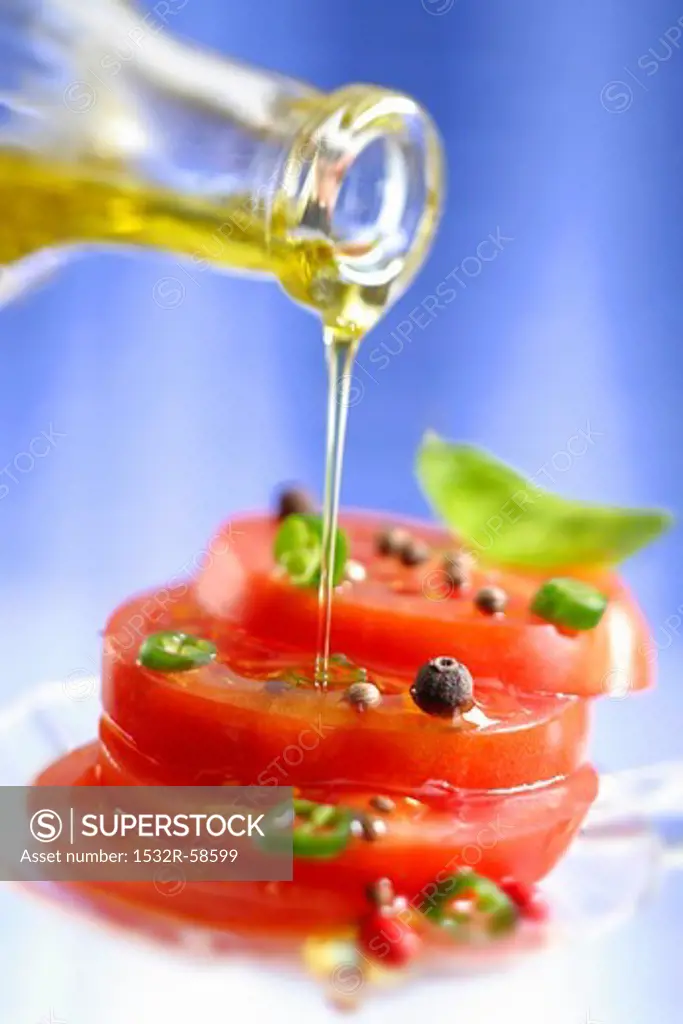 Spiced tomatoes being drizzled with olive oil