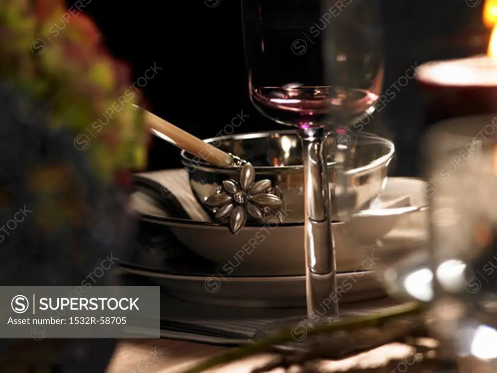 A festive place setting with a silver bowl and a wine glass