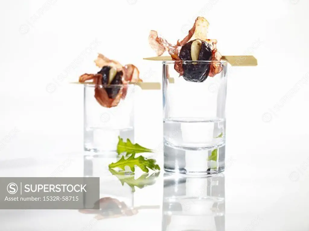 Grilled plums wrapped in salami on schnapps glasses