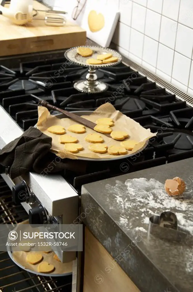 Baked heart biscuits on baking trays in a kitchen