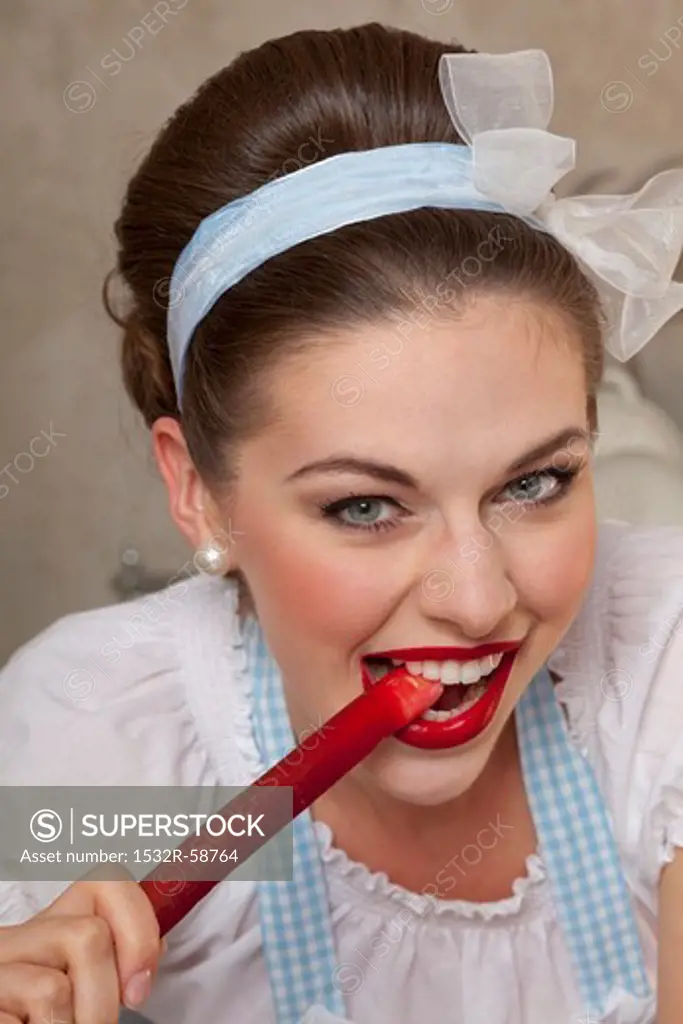 A retro-style girl bitting into a stalk of rhubarb