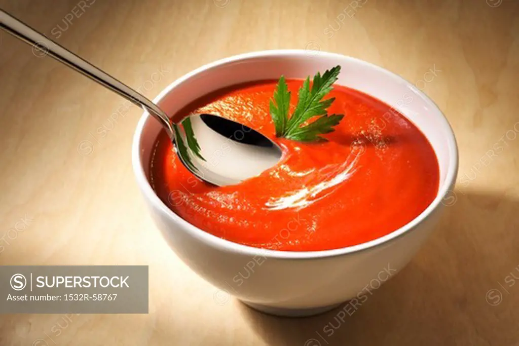 A bowl of tomato soup with a spoon