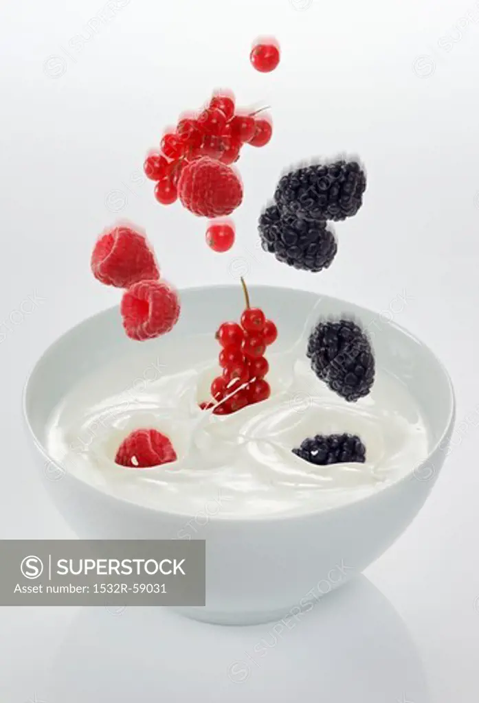 Berries falling into a bowl of yogurt