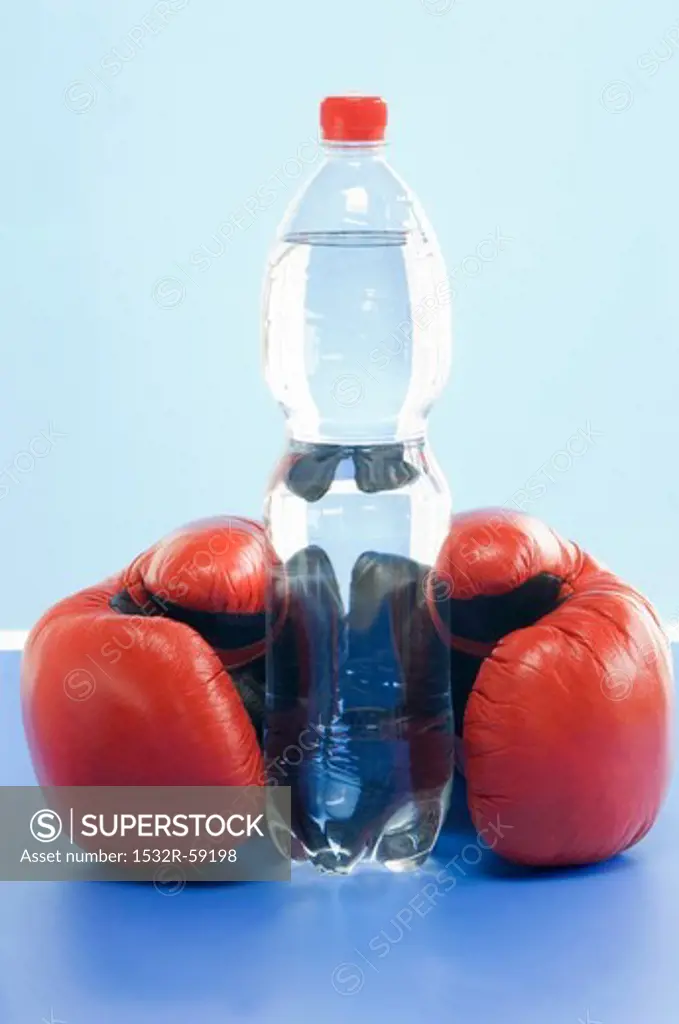 A bottle of mineral water and a pair of boxing gloves