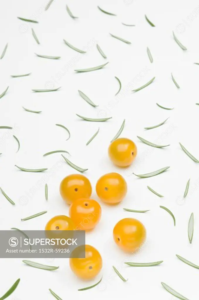 Yellow cherry tomatoes and scattered rosemary leaves