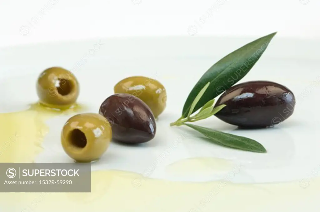 Olives with leaves and olive oil on a plate