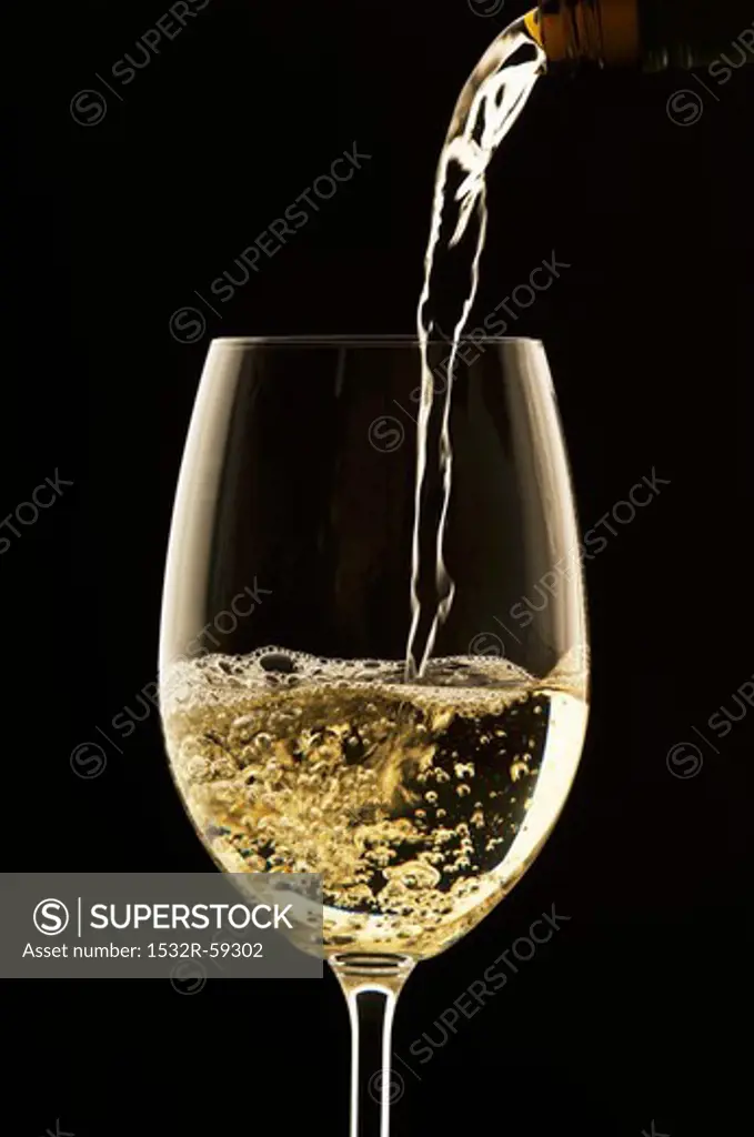 White Wine Pouring from Bottle into Glass; White Background