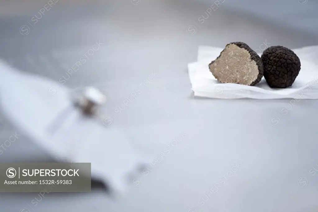 Black truffles, halved, on paper, on a truffle slice