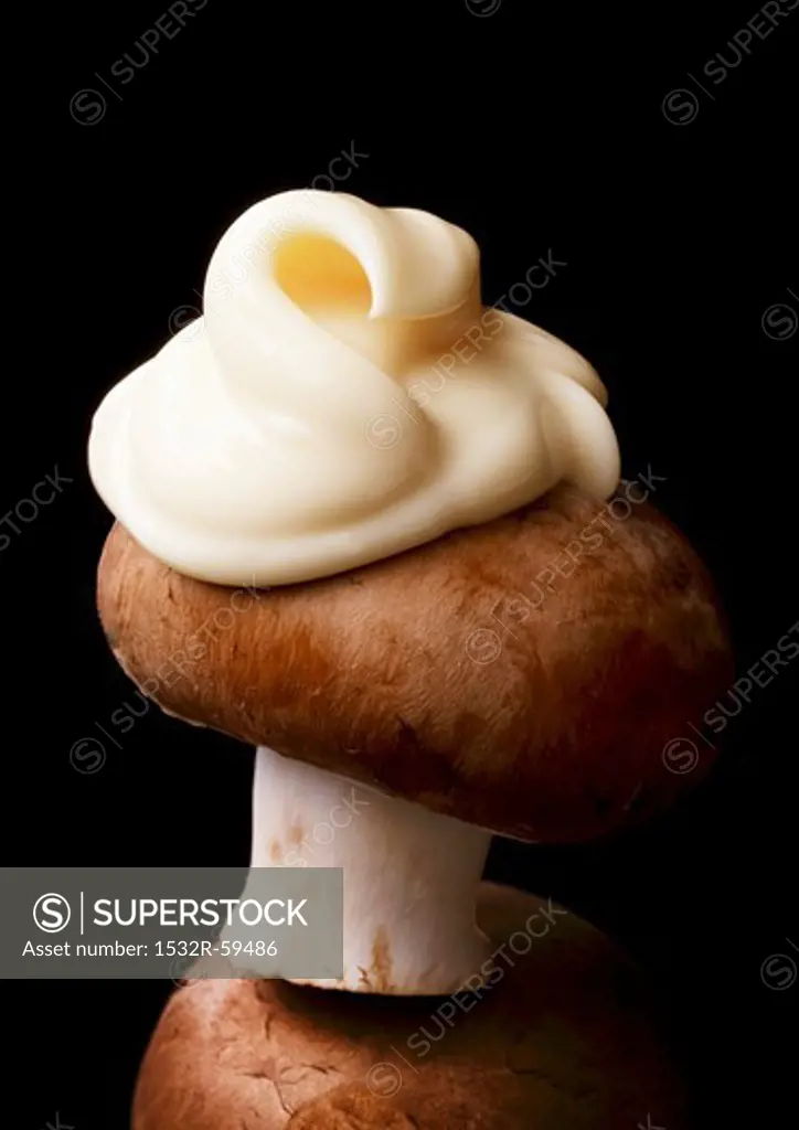 A brown mushroom with a dollop of mayonnaise