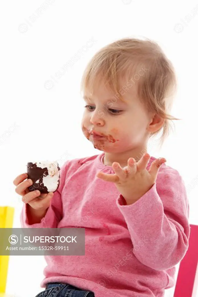 A small child eating a chocolate marshmallow