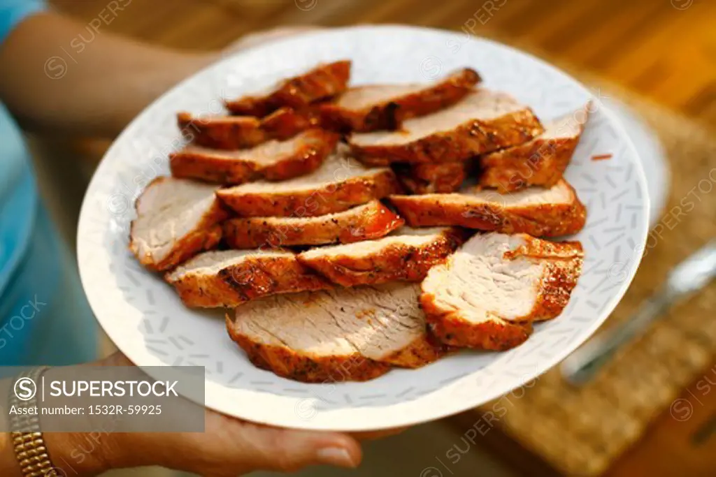 Woman Carrying a Platter of Sliced Grilled Pork Tenderloin