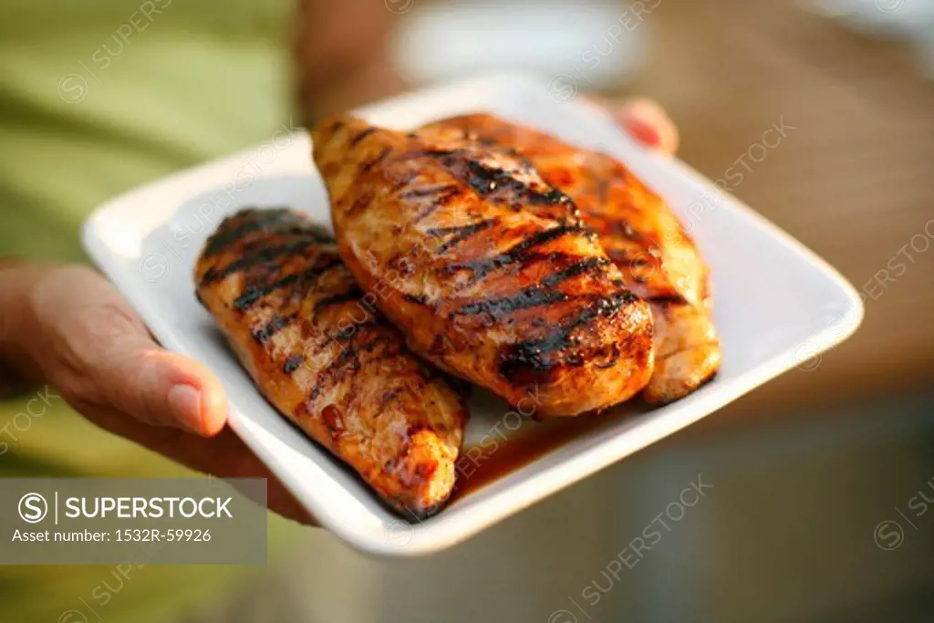 Woman Holding a Platter with Three Grilled Chicken Breasts