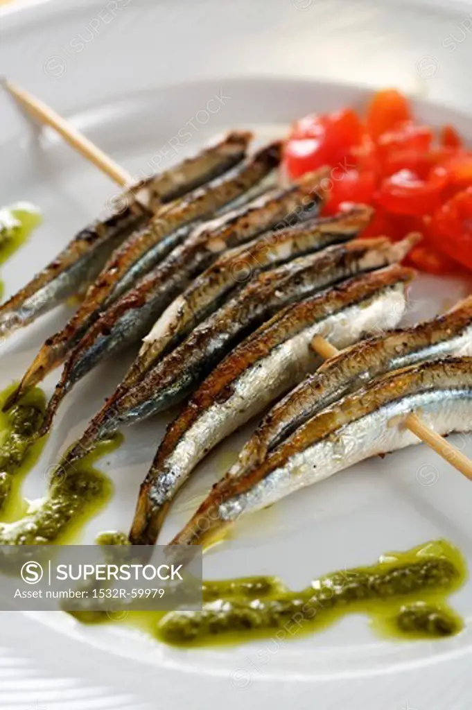 Grilled sardines on a skewer with pesto and tomato salad