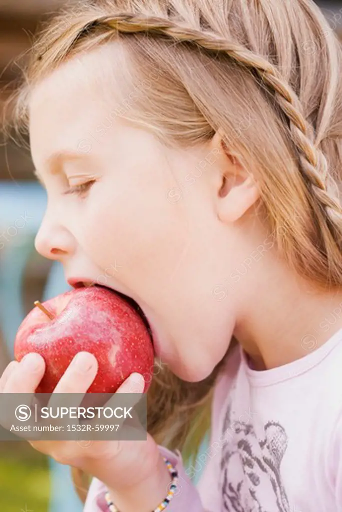 A girl biting into an apple