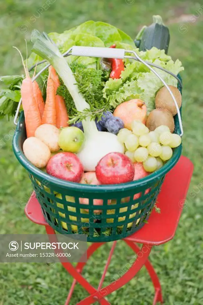 A basket of fresh fruit and vegetables on a garden table